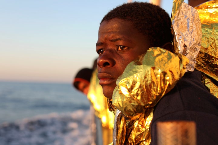 A migrant, covered with a thermal blanket, gazes at the sea aboard a boat operated by the Spanish NGO Proactiva Open Arms fol