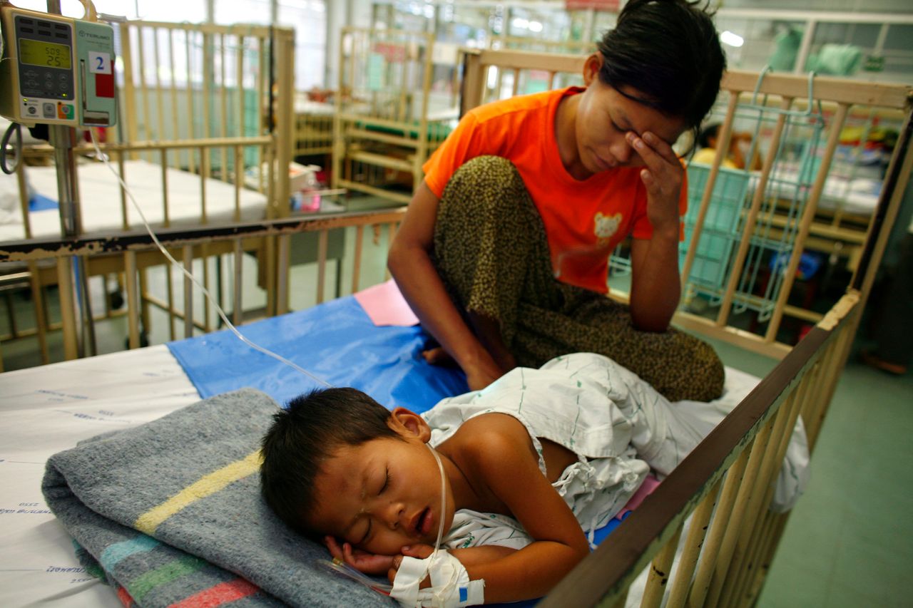 A woman from Myawaddy, Myanmar, sits with her son suffering from dengue fever in Mae Sot, Thailand, on Oct. 30, 2007.