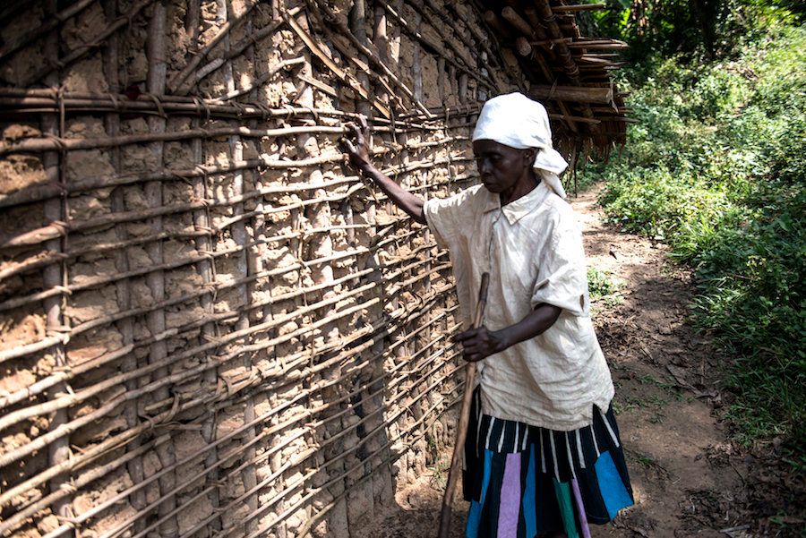 Mapuani, who lost her vision to river blindness, feels her way to the outhouse.