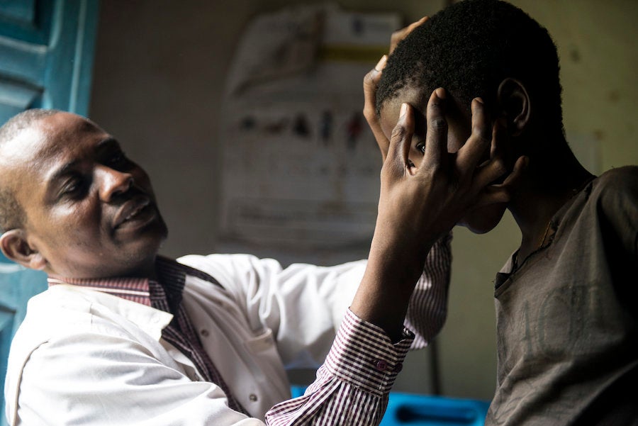 A Congolese doctor examines a nodule full of worms on a boy's head.