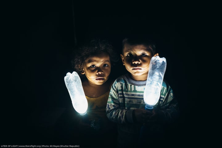 Two kids holding Liter of Light bottles with a solar-powered LED inside.