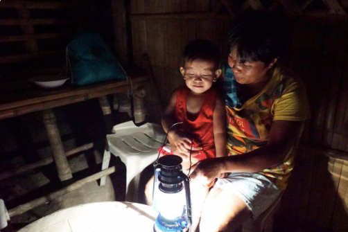 A family sitting by a solar-converted kerosene lamp from Liter of Light.