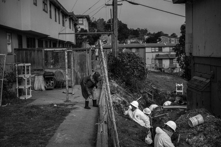 Some of the thousands of sites poisoned by the military’s handling of munitions waste are smack in the middle of residential neighborhoods. Above, a resident talks with construction workers in protective gear in the contaminated Hunters Point neighborhood of San Francisco, California.