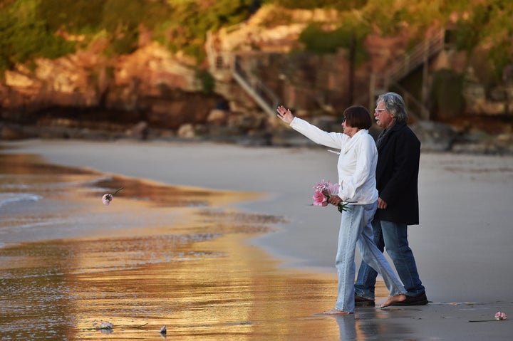 The parents of Justine Damond, John Ruszczyk and Maryan Heffernan, throw a flower into the water during a vigil for their daughter at Freshwater Beach on July 19, 2017 in Sydney.