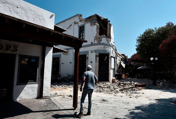 A pedestrian looks at the ruins of a bar on the island of Kos