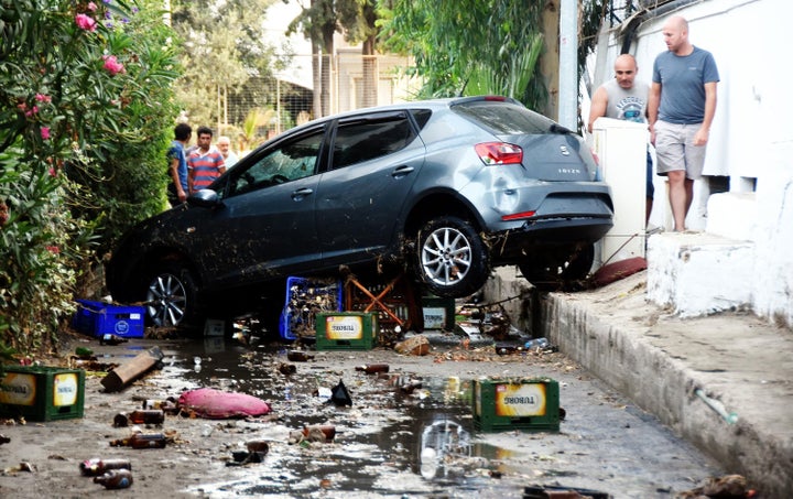 <strong>People look at a damaged car following a sea surge caused by the quake in Bodrum</strong>