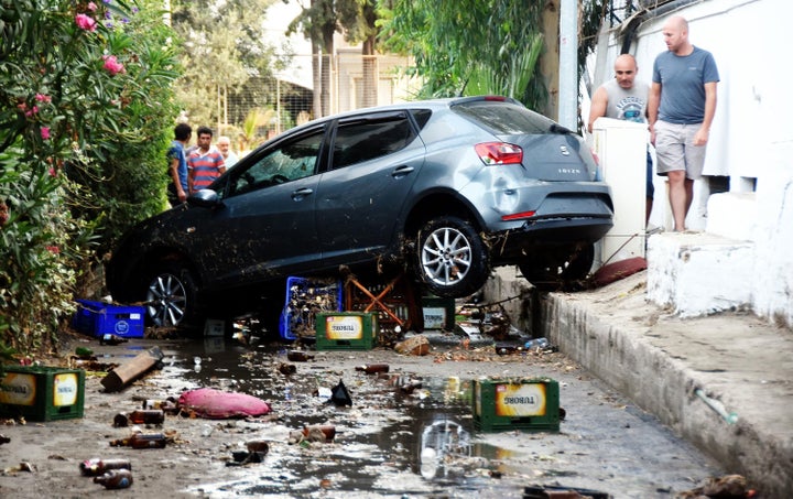 People look at a damaged car following a sea surge caused by the quake in Bodrum