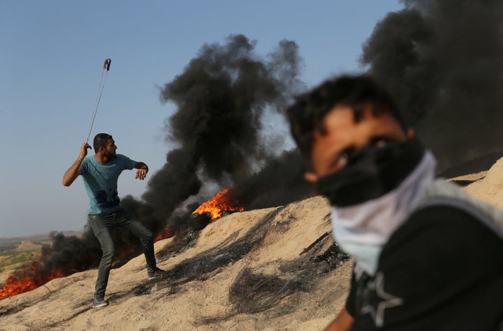 A Palestinian protester uses a sling to hurl stones towards Israeli troops during clashes near the border between Israel and central Gaza Strip July 21, 2017. 