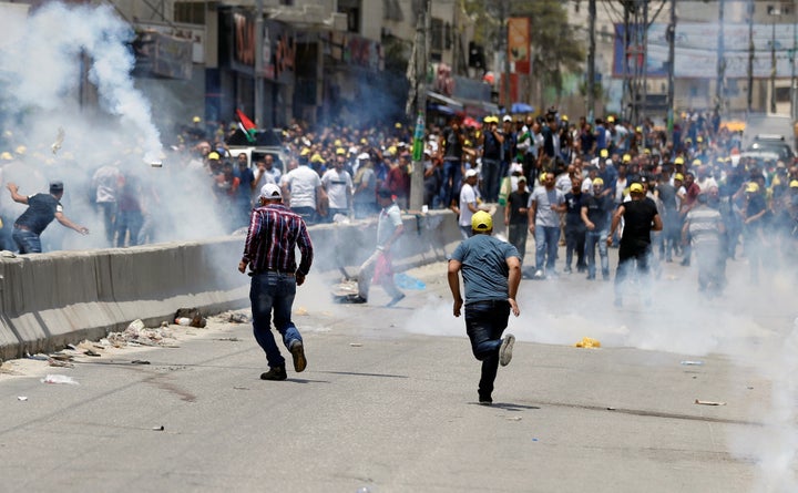 Palestinian protesters react to tear gas fired by Israeli troops during clashes near Qalandiya checkpoint near the West Bank city of Ramallah July 21, 2017. 