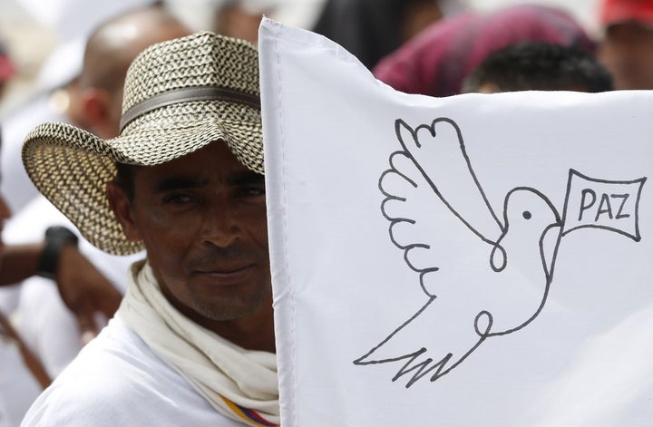 A FARC member waves a white peace flag to commemorate the completion of their disarmament.