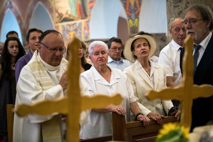 Marcelin Dumoulin's stepdaughter, Annette Dumoulin (C-L), is seen with one of the couple's daughters, Marcelline Udry (C-R), during the service on Saturday.