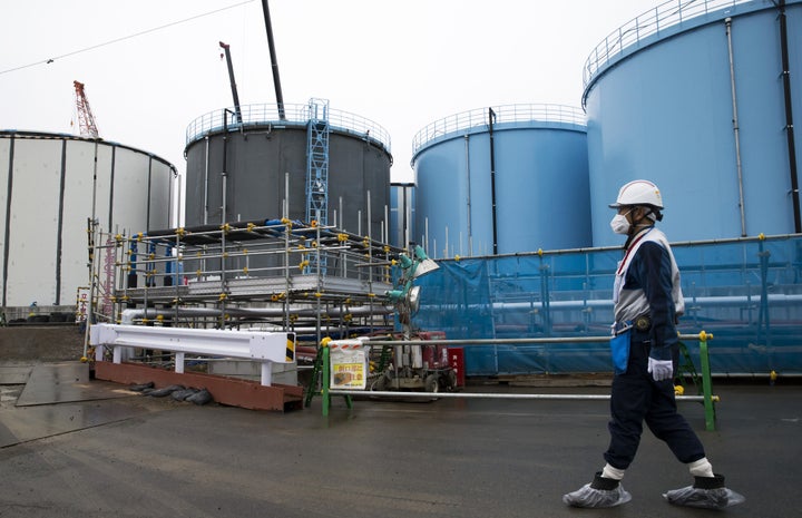 An employee walks past storage tanks for contaminated water at the Tokyo Electric Power Co.'s Fukushima Dai-ichi nuclear power plant in Okuma last February.