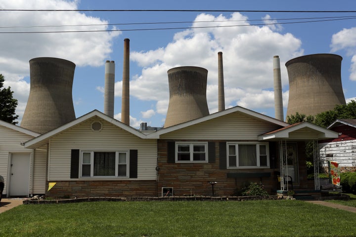 The John Amos coal-fired power plant rises behind a home in Poca, West Virginia, in 2014.