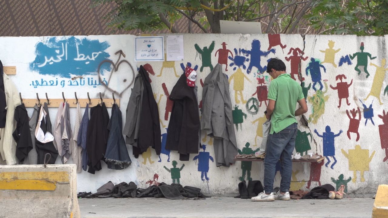 A man in Beirut leaves clothes at the wall of kindness