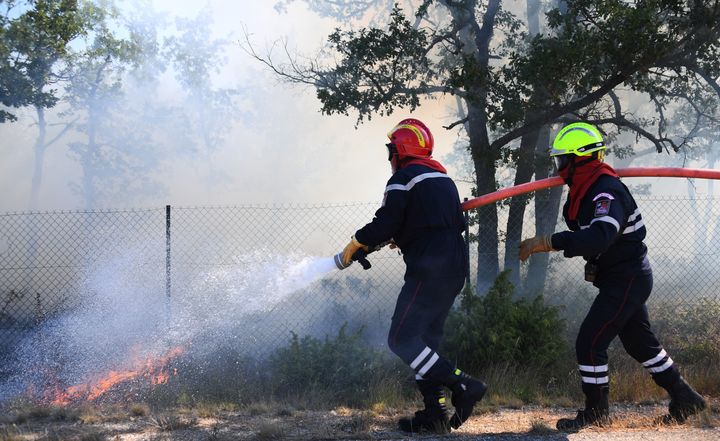 Firefighters try to extinguish a fire burning in Artigues, southeastern France