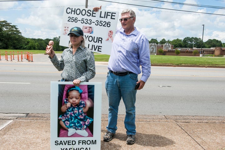Anti-abortion protesters outside a clinic in Huntsville, Alabama, hold signs featuring a child they claim they "saved" from a