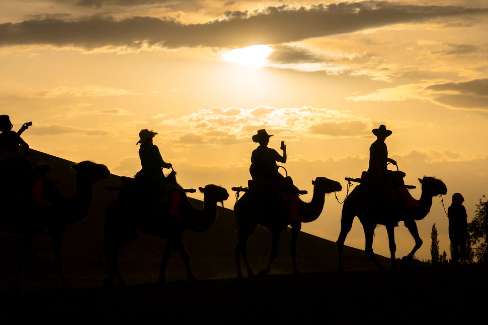 Tourists ride camels in the Mingsha Shan desert, part of the ancient Silk Roads, during the Silk Road International Cult