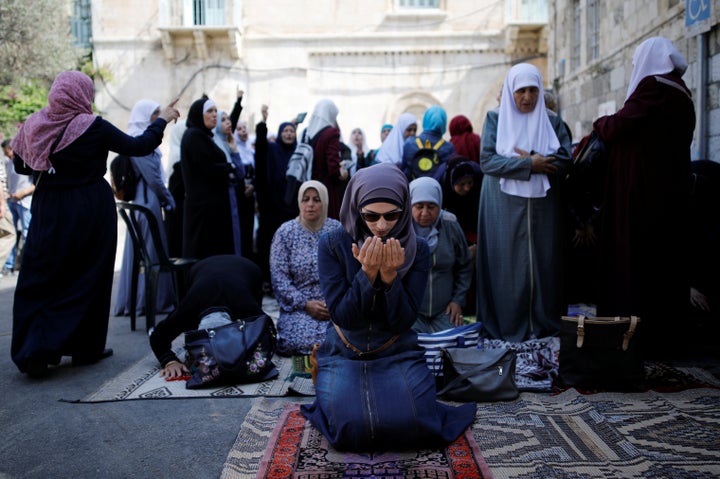 Palestinian women pray as others shout slogans outside the compound known to Muslims as Noble Sanctuary and to Jews as Temple