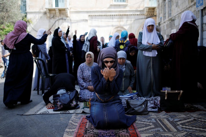 Palestinian women pray as others shout slogans outside the compound known to Muslims as Noble Sanctuary and to Jews as Temple Mount, in Jerusalem's Old City.