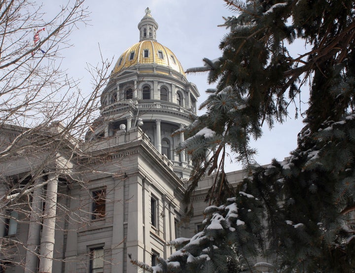 The dome of the Colorado Statehouse is framed between trees.