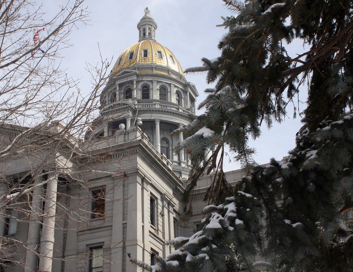 The dome of the Colorado Statehouse is framed between trees. 