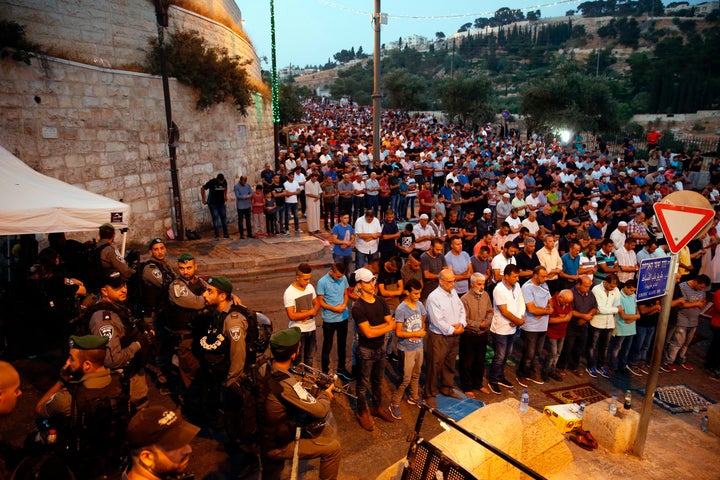 Israeli security forces stand by as Palestinian Muslim worshippers pray outside Lions' Gate, a main entrance to the Al-Aqsa mosque compound in Jerusalem's Old City, on July 24, 2017, in protest against new Israeli security measures implemented at the holy site following an attack that killed two Israeli policemen the previous week. 