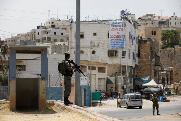 An Israeli border police officer stands guard near a disputed building (in background with banner displayed on it) where about a hundred hard-line Jewish settlers have hunkered down, in the West Bank city of Hebron July 26, 2017. 