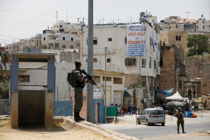 An Israeli border police officer stands guard near a disputed building (in background with banner displayed on it) where abou