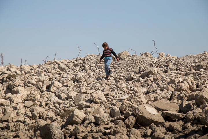 A girl walks amongst the remains of destroyed buildings outside in Hammam al-Alil, a town roughly 25 kilometers south of Mosu