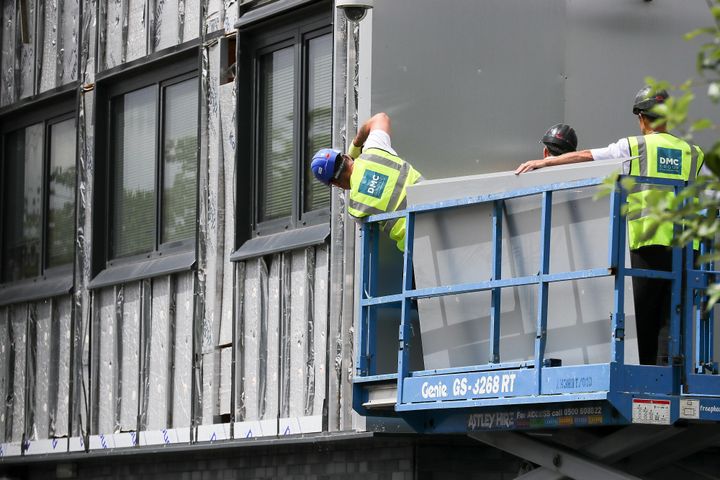 Workers remove cladding for testing from one of the tower blocks in Salford