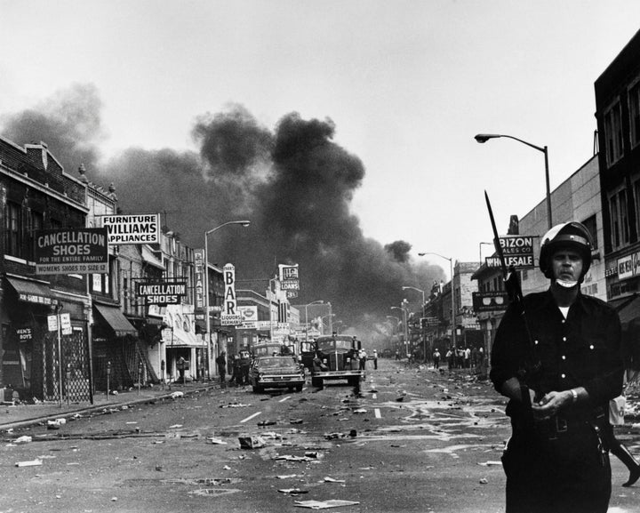 A policeman stands guard in a Detroit street on July 25, 1967, as buildings are burning during riots that erupted following a police operation.