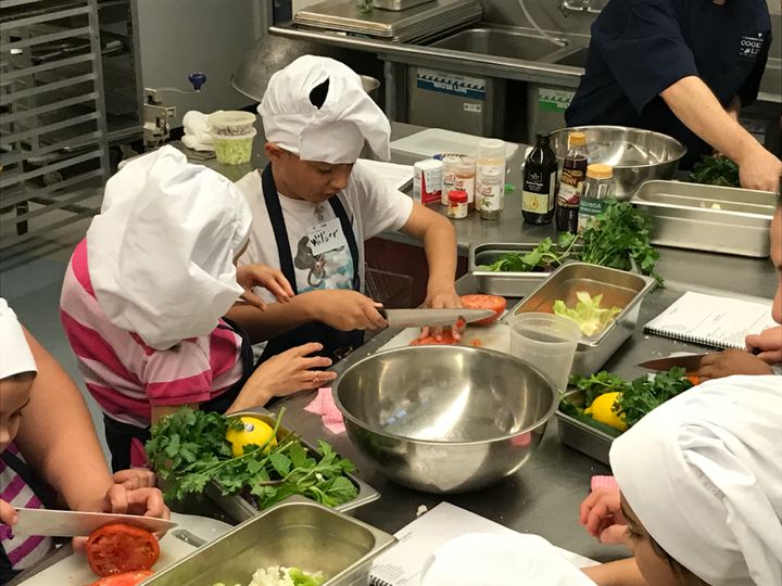 Children sharpen their knife skills while preparing a refreshing salad during a Common Threads Cooking Skills & World Cuisine class.