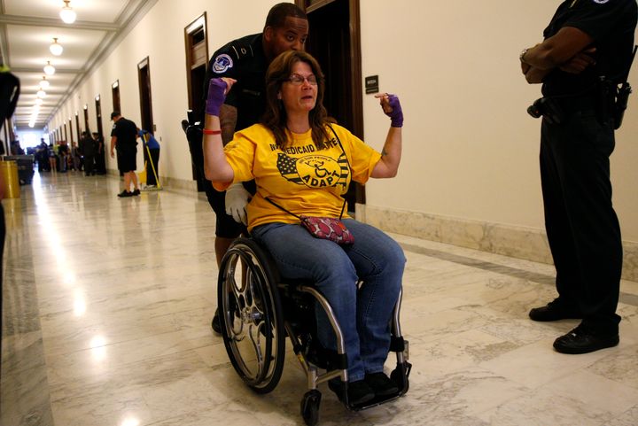 A protester calling for "no cuts to Medicaid" is escorted away by police after being arrested during a demonstration outside Senate Majority Leader Mitch McConnell's office.