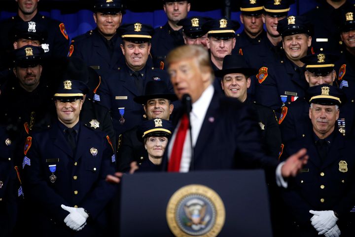 Police officers laugh at a line by President Donald Trump as he delivers remarks at the Long Island University campus in Brentwood, New York, on Friday.