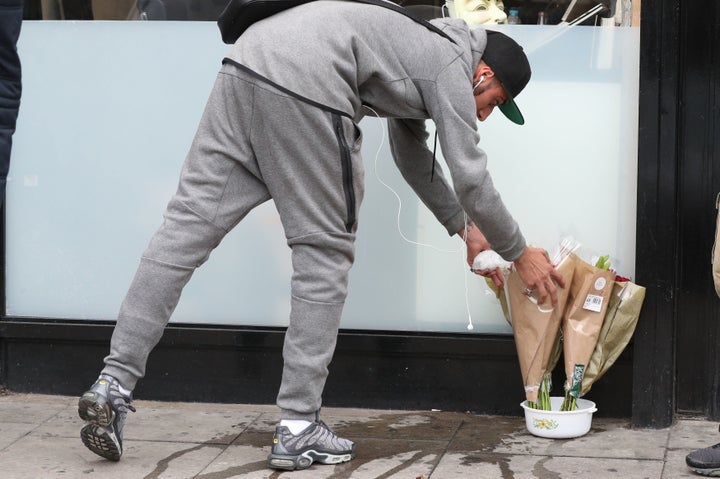 A man lays flowers outside the Kingsland Road shop where Rashan Charles was chased and apprehended, shortly before his death