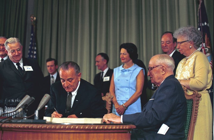 President Lyndon B. Johnson signs Medicare and Medicaid into law.