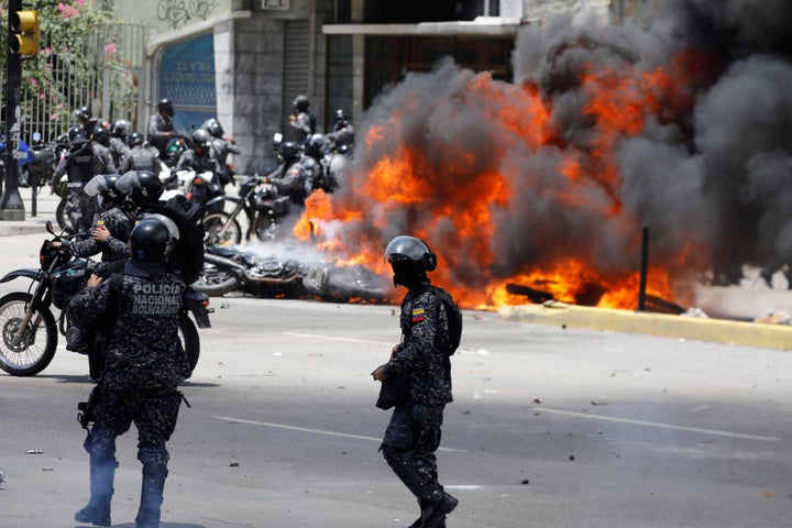 Security forces members stand near burning motorcycles as clashes break out while the Constituent Assembly election is being