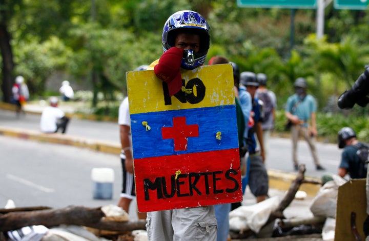 An opposition supporter holds a shield that reads "No more deaths" as clashes break out during Sunday's elections. Caracas. July 30, 2017.