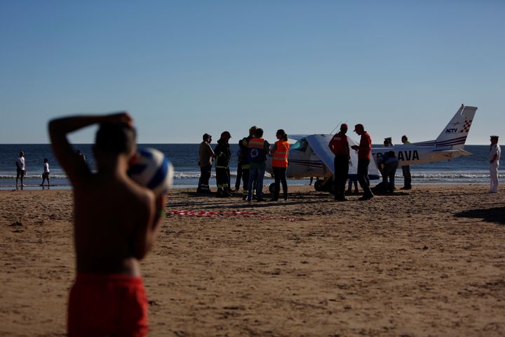 People surround the plane, which killed two people as it landed on Sao Joao Beach