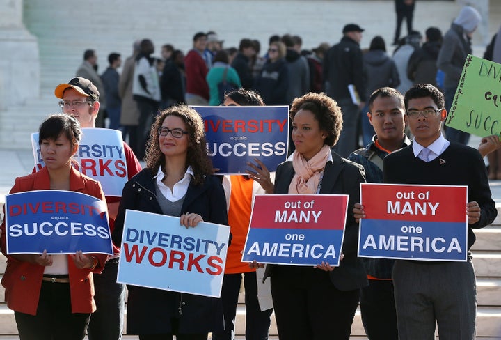 Protesters hold signs in front of the U.S. Supreme Court prior to the high court's arguments on Fisher v. University of Texas at Austin.