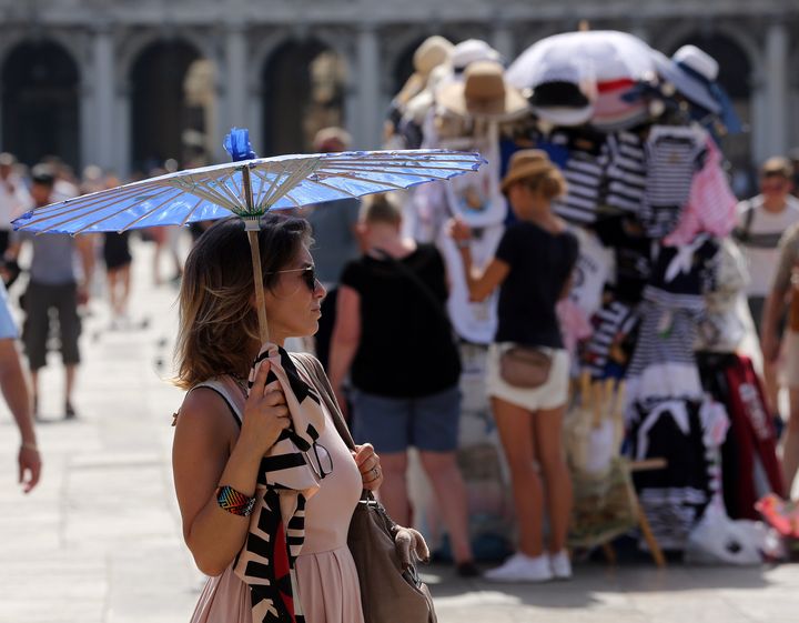 A woman shelters from the sun in St. Mark's Square in Venice, Italy, 3 August 