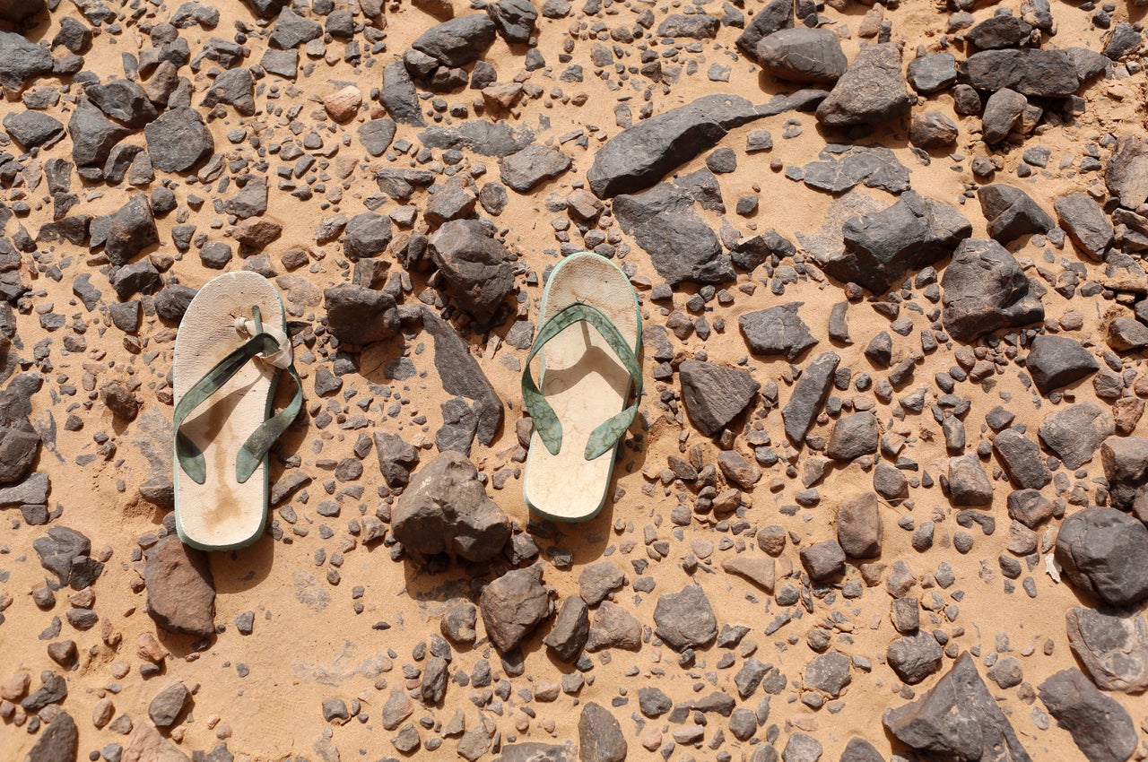 A pair of flip flops, which were left behind by a migrant, lie on the ground in the desert near the border between Algeria and Libya.