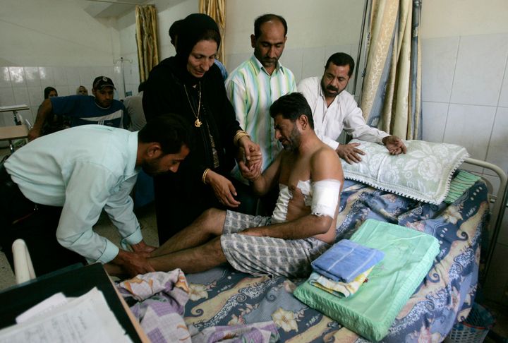 A man who was wounded in a shooting attack by the security guards of Blackwater firm on Sunday, is helped by his relatives in a hospital in Baghdad, September 20, 2007.