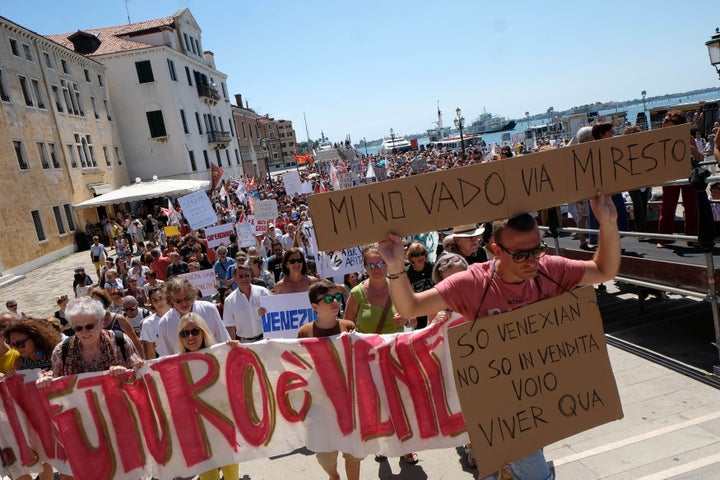 A resident holds a placard "I don't want to go, i'm staying" during a protest in Venice, Italy, July 2, 2017. 