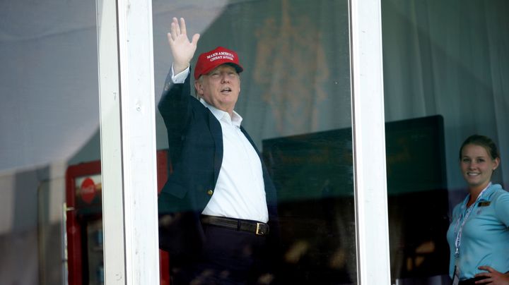 From his personal enclosure at his Bedminster, New Jersey, golf club, President Donald Trump waves to supporters during the U.S. Women's Open on July 15, 2017.