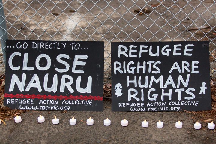 Two banners and candles at the gates of a refugee detention centre during a candlelight vigil as protestors stand in solidarity with refugees in detention. 