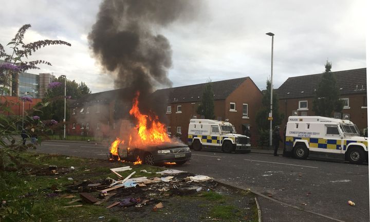 A parked car set alight by youths burns on Stewart Street in Belfast