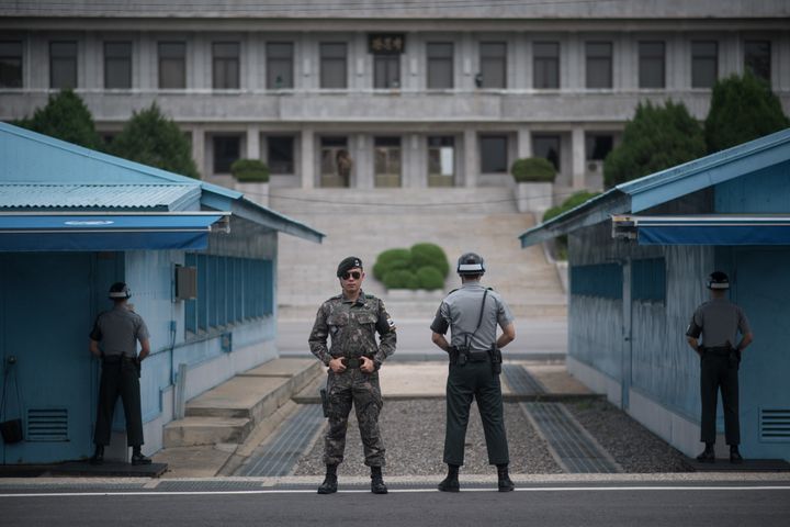South Korean soldiers stand guard before North Korea's Panmon Hall (rear C) and the military demarcation line separating North and South Korea, at Panmunjom, in the Joint Security Area (JSA) of the Demilitarised Zone (DMZ)