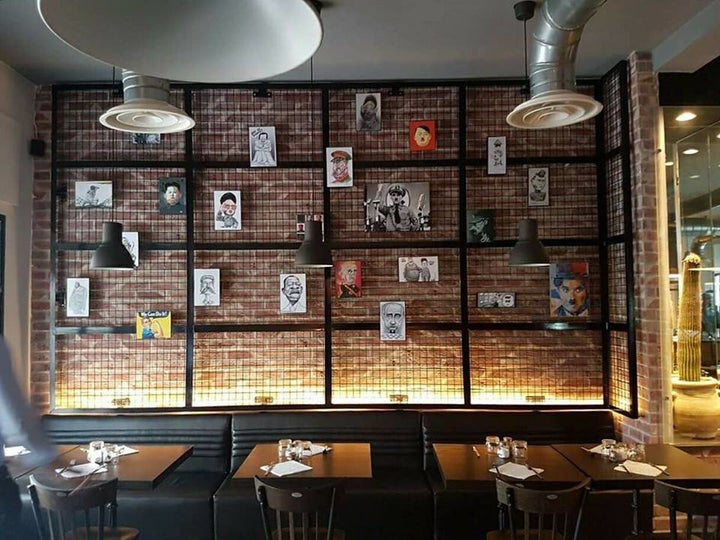 A wall of cartoon portraits in the Restaurant Le Dictateur.