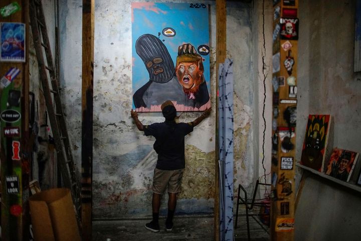 Cuban artist Fabian Lopez shows one of his paints with his character holding Donald Trump's head in his atelier in Havana, Cuba.
